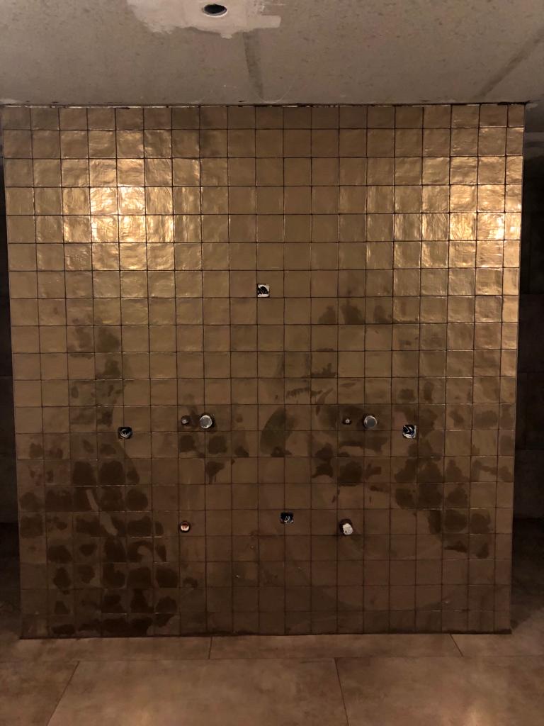 Douchewand met gouden mozaïektegels in aanleg